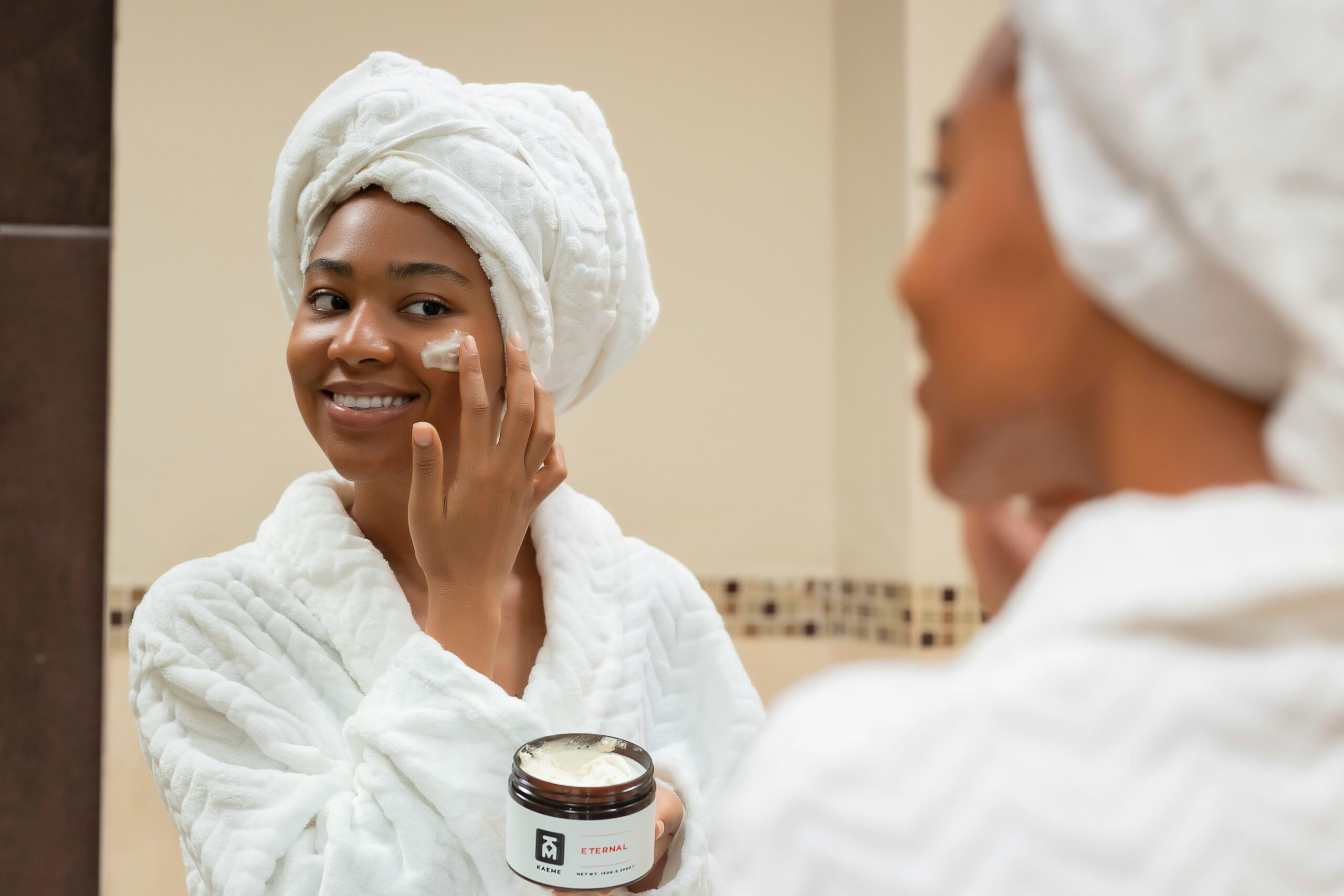 a woman with a towel on her head and a jar of cream on her f